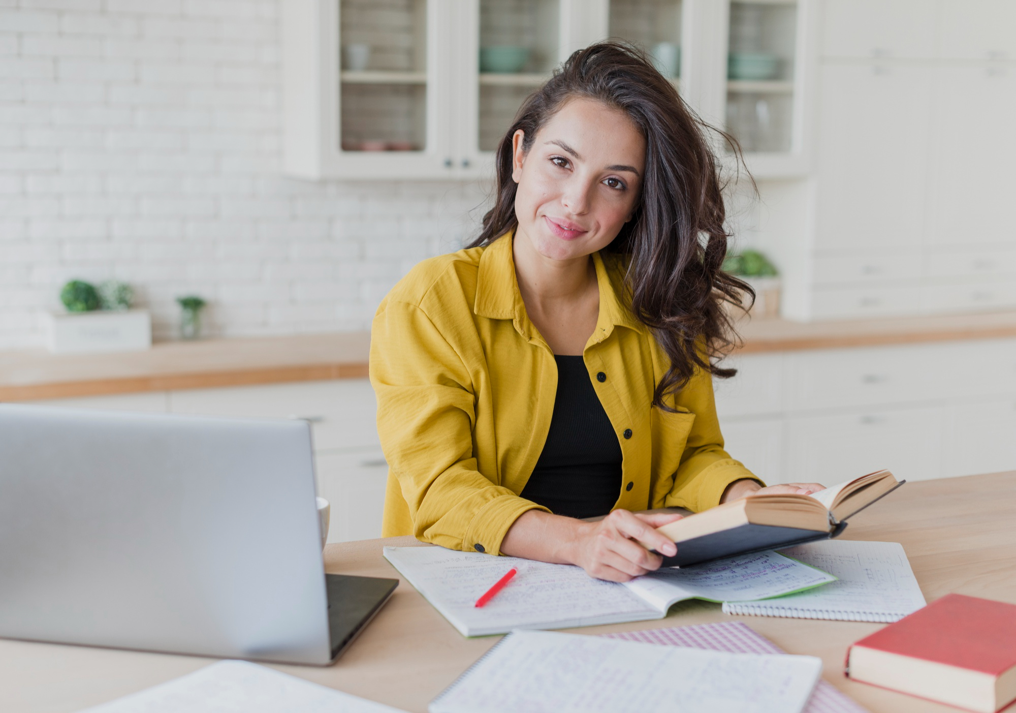 Mujer estudiando con libros y un ordenador.